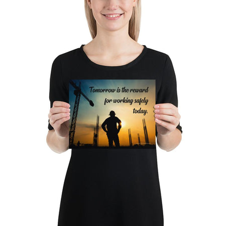 A safety poster showing a worker on a construction site being silhouetted by a sunset of orange and blue colors with the slogan tomorrow is the reward for working safely today.