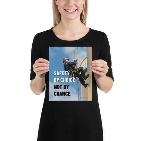 A fully harnessed man wearing a hard hat scaling the side of a building with a bright blue sky and clouds in the background with the text safety by choice, not by chance in bold text to his left.