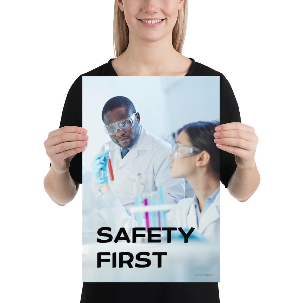 A safety poster showing two lab workers collaborating on a project in a lab while wearing full PPE with the slogan safety first.