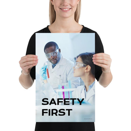 A safety poster showing two lab workers collaborating on a project in a lab while wearing full PPE with the slogan safety first.