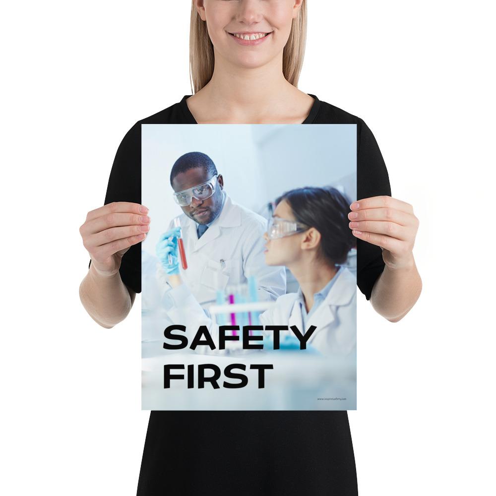 A safety poster showing two lab workers collaborating on a project in a lab while wearing full PPE with the slogan safety first.