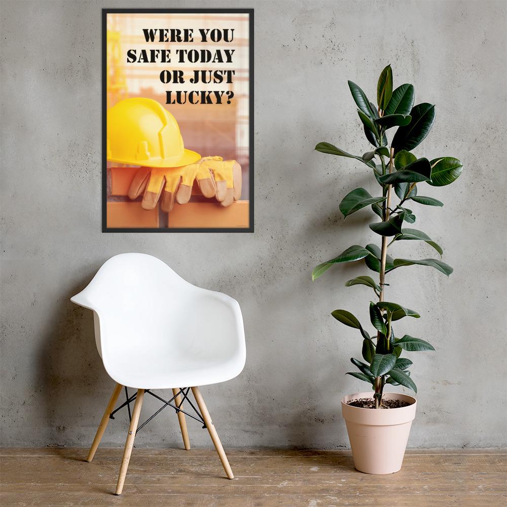 A workplace safety poster showing a yellow hard hat and some gloves sitting on a brick wall on a construction site with the slogan were you safe today, or just lucky written in black stencil font.