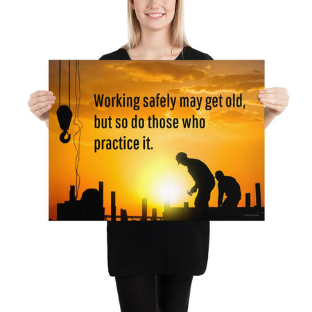 A workplace safety poster showing a construction site and construction workers being silhouetted by a bright and beautiful sunset of different shades of orange with the slogan working safely may get old, but so do those who practice it.