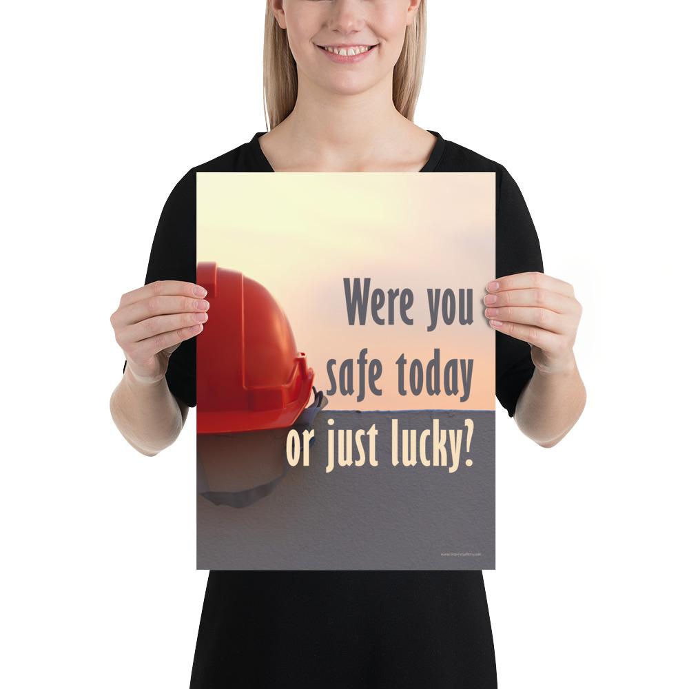 A workplace safety poster showing a red hard hat sitting on a grey wall with a dreamy sunset background and the slogan were you safe today, or just lucky?