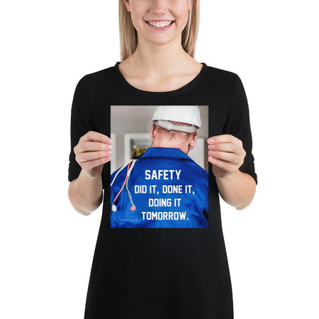 Safety poster showing an electrician wearing a hard hat and holding cables working on an electrical panel with text on the back of his bright blue shirt.