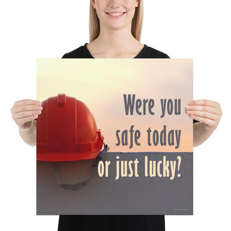 A workplace safety poster showing a red hard hat sitting on a grey wall with a dreamy sunset background and the slogan were you safe today, or just lucky?