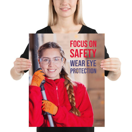 An eye safety poster of a young woman wearing safety glasses and orange gloves smiling as she works in a warehouse with a safety slogan in the top right corner.