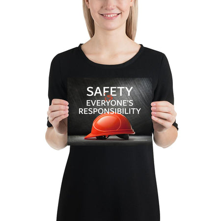 A workplace safety poster showing a red hard hat in front of a grey, industrial-looking background with the slogan safety is everyone's responsibility.