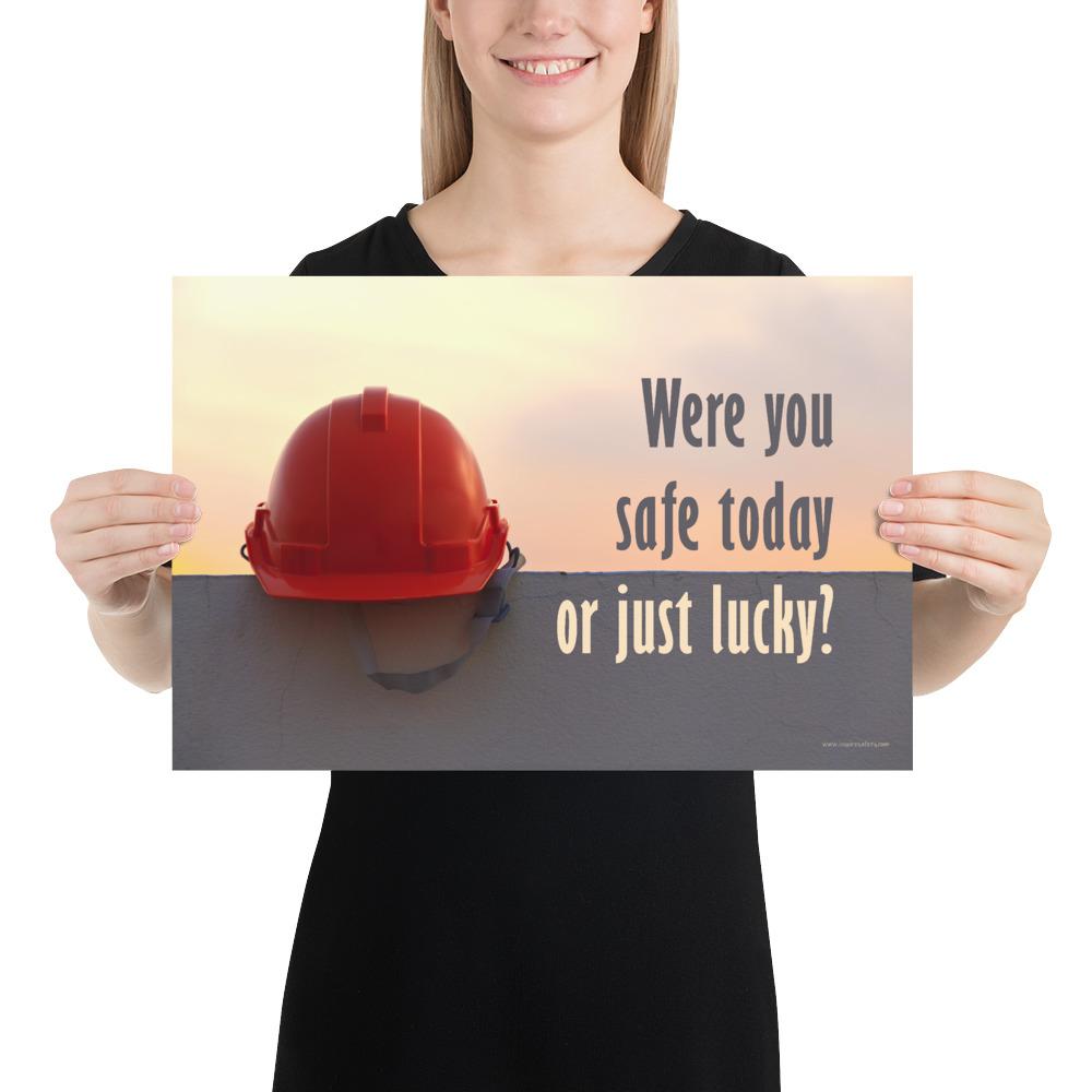 A workplace safety poster showing a red hard hat sitting on a grey wall with a dreamy sunset background and the slogan were you safe today, or just lucky?