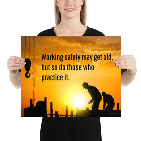 A workplace safety poster showing a construction site and construction workers being silhouetted by a bright and beautiful sunset of different shades of orange with the slogan working safely may get old, but so do those who practice it.