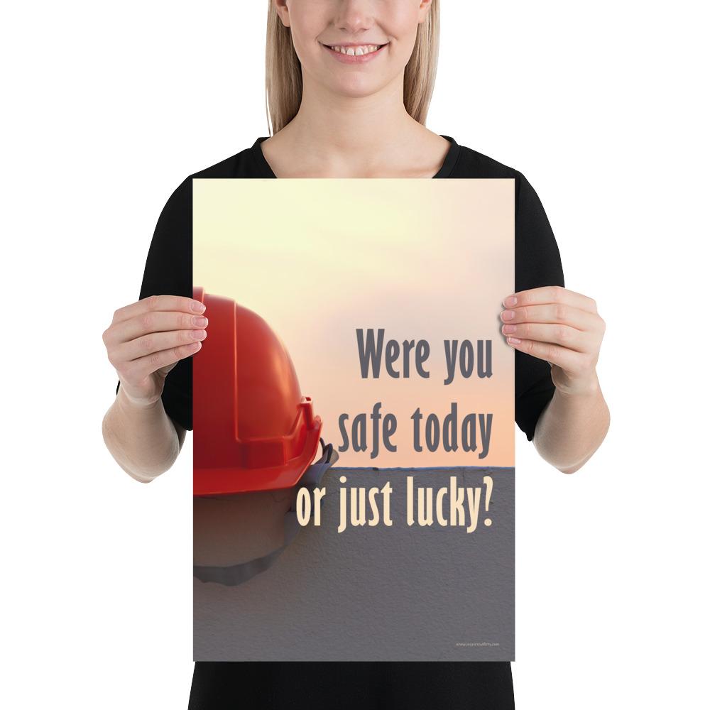 A workplace safety poster showing a red hard hat sitting on a grey wall with a dreamy sunset background and the slogan were you safe today, or just lucky?