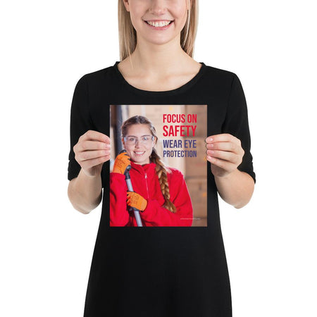 An eye safety poster of a young woman wearing safety glasses and orange gloves smiling as she works in a warehouse with a safety slogan in the top right corner.