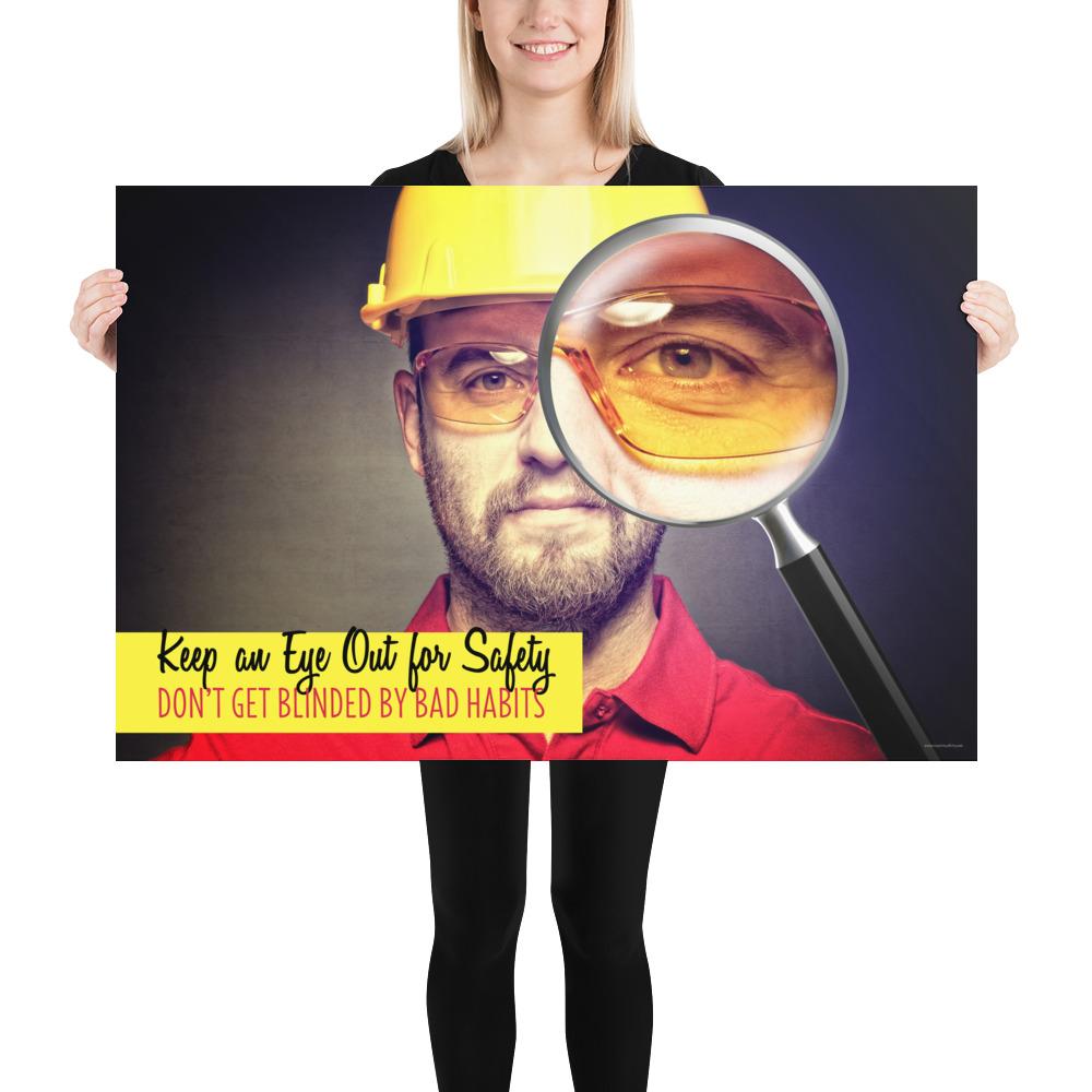 A workplace safety poster showing a portrait of a man wearing a hardhat and safety glasses with a magnifying glass magnifying one eye with the slogan, keep an eye out for safety, don't get blinded by bad habits.
