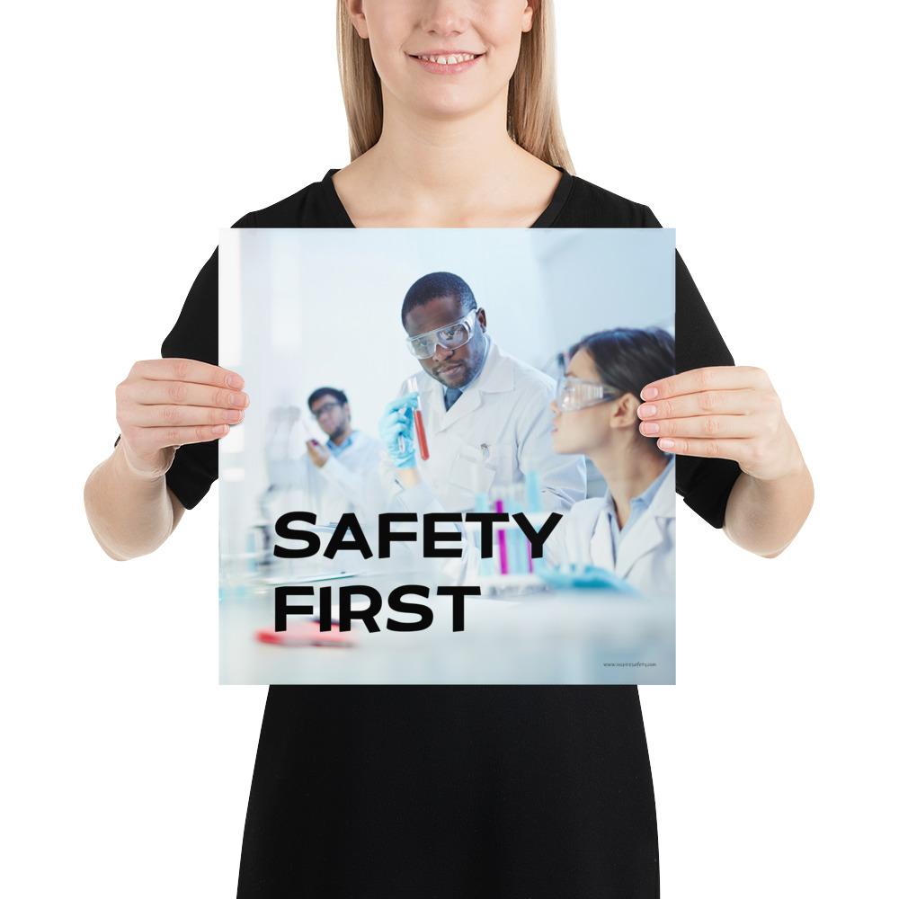 A safety poster showing two lab workers collaborating on a project in a lab while wearing full PPE with the slogan safety first.