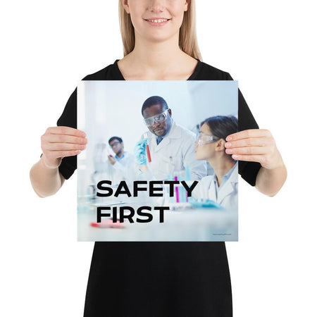 A safety poster showing two lab workers collaborating on a project in a lab while wearing full PPE with the slogan safety first.