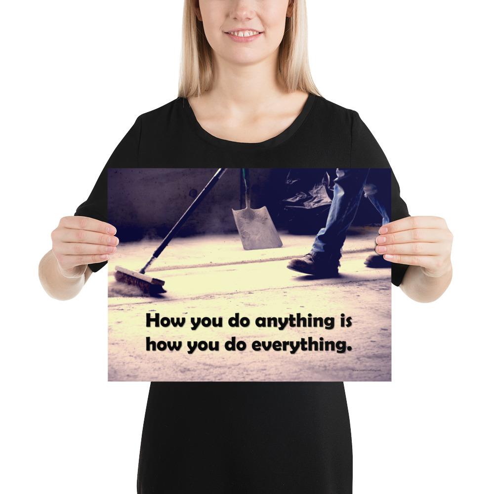 Safety poster showing a closeup of the ground where a warehouse or construction worker is sweeping the workshop floor and an encouraging safety slogan written in bold text.