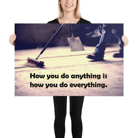 Safety poster showing a closeup of the ground where a warehouse or construction worker is sweeping the workshop floor and an encouraging safety slogan written in bold text.