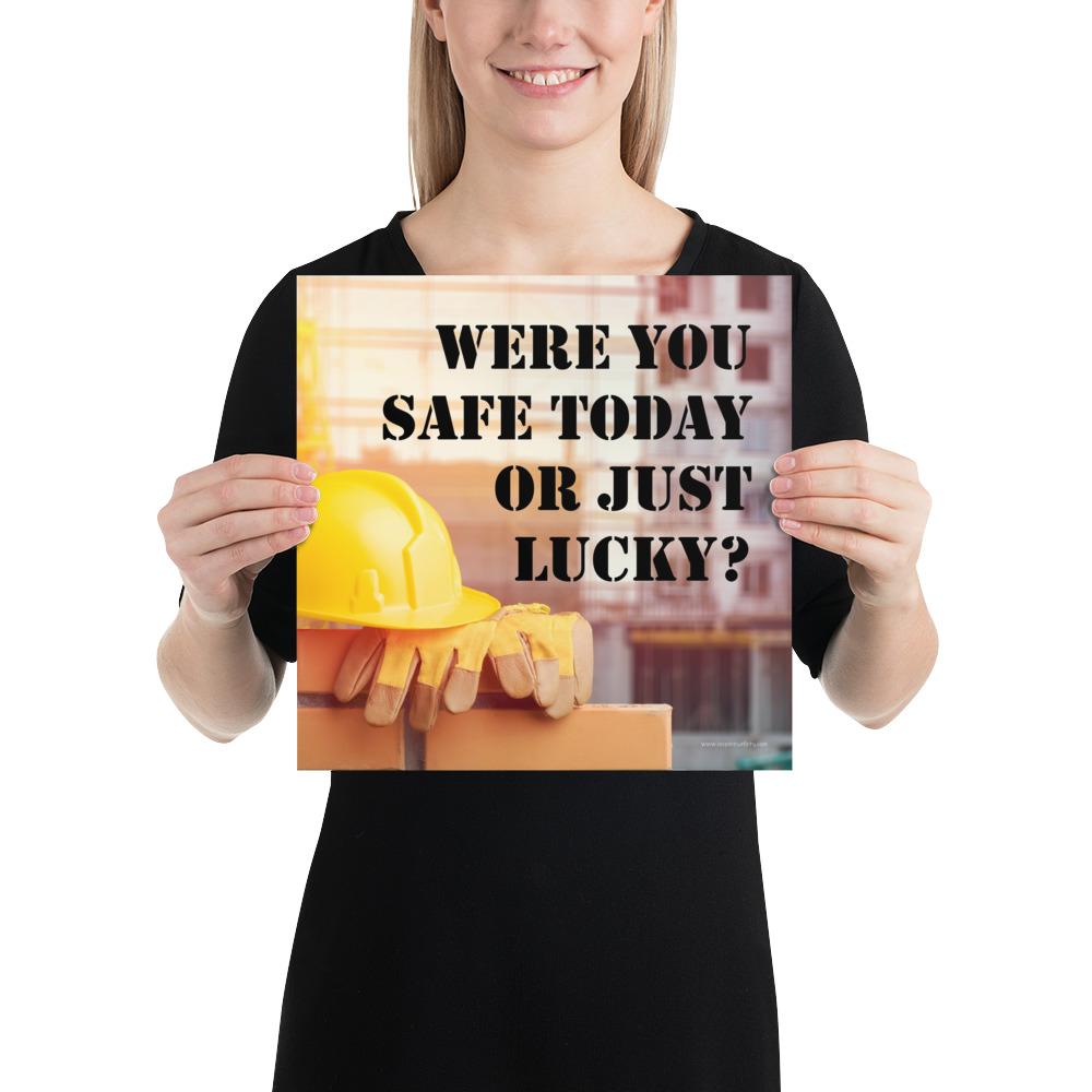 A workplace safety poster showing a yellow hard hat and some gloves sitting on a brick wall on a construction site with the slogan were you safe today, or just lucky written in black stencil font.