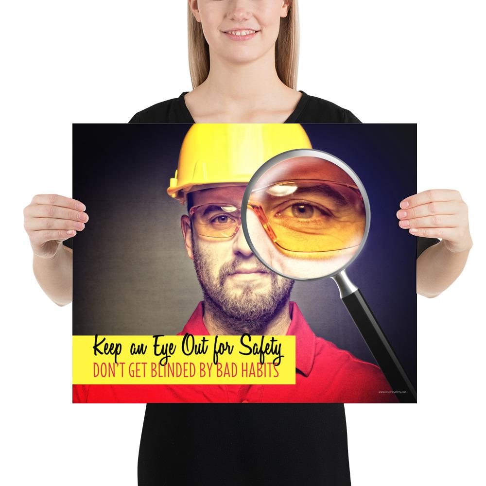 A workplace safety poster showing a portrait of a man wearing a hardhat and safety glasses with a magnifying glass magnifying one eye with the slogan, keep an eye out for safety, don't get blinded by bad habits.