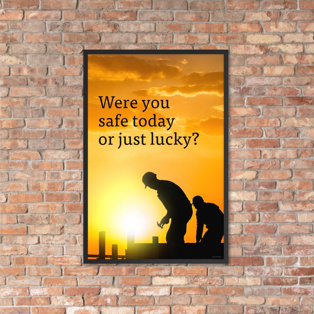 A workplace safety poster showing workers on a construction site being silhouetted in black with a sunset of orange hues in the background with the slogan were you safe today, or just lucky?
