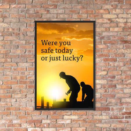 A workplace safety poster showing workers on a construction site being silhouetted in black with a sunset of orange hues in the background with the slogan were you safe today, or just lucky?