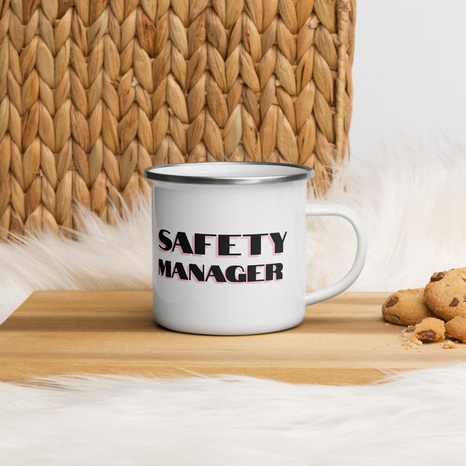 White metal mug with a silver rim with "Safety Manager" in bold text with a pink drop shadow across the side.
