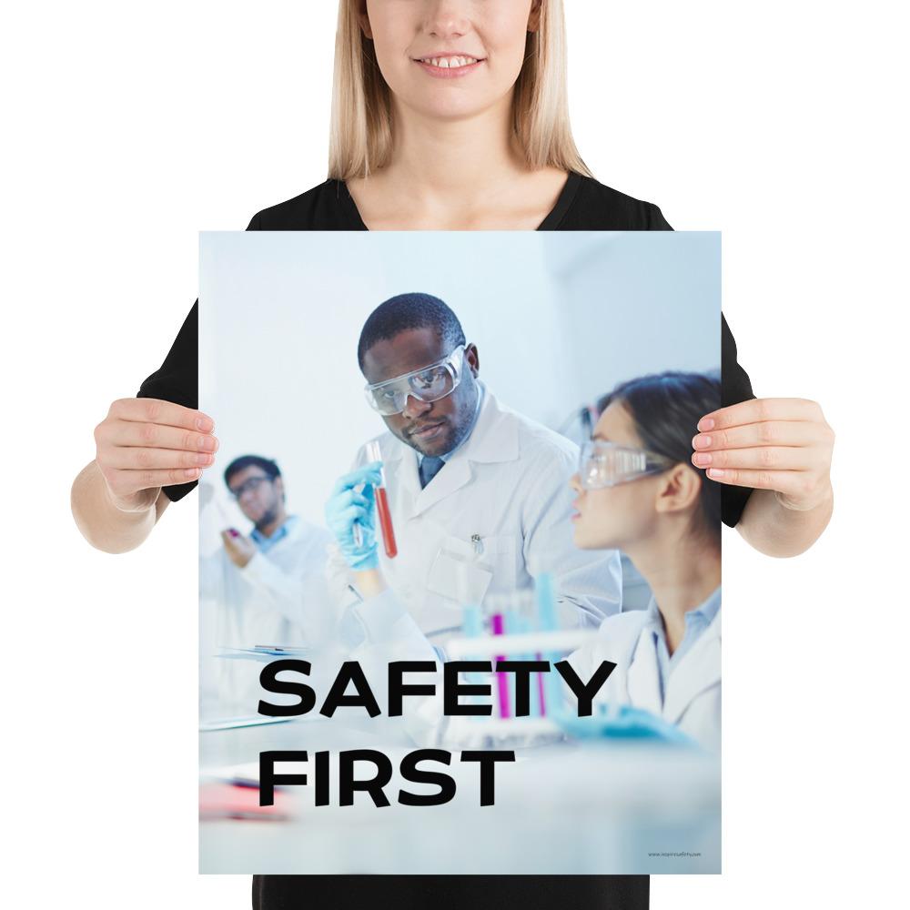 A safety poster showing two lab workers collaborating on a project in a lab while wearing full PPE with the slogan safety first.