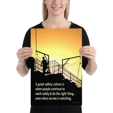 A construction safety poster showing the silhouette of a construction worker working on a building with a bright yellow sunset in the background and a safety slogan in the bottom left corner.