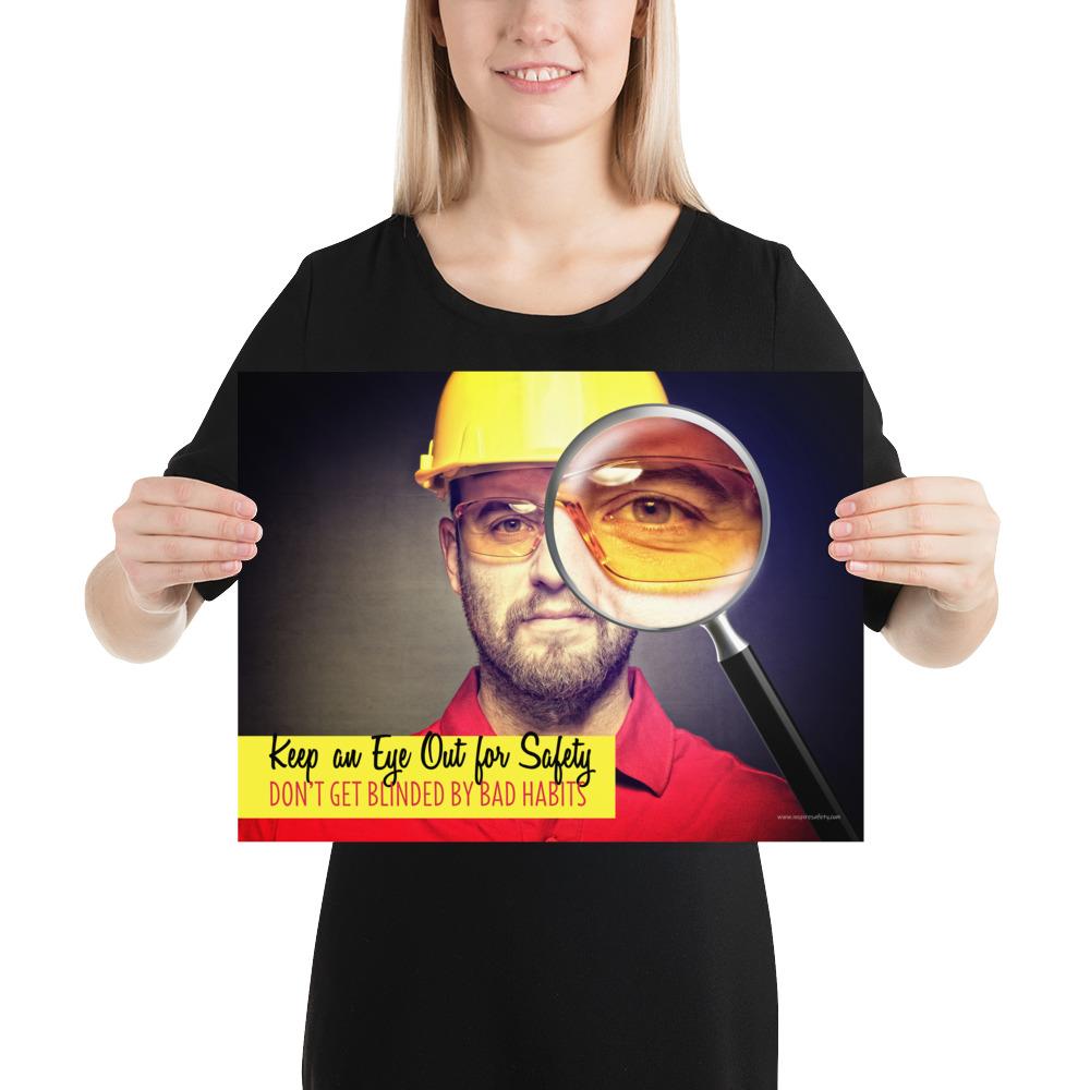 A workplace safety poster showing a portrait of a man wearing a hardhat and safety glasses with a magnifying glass magnifying one eye with the slogan, keep an eye out for safety, don't get blinded by bad habits.