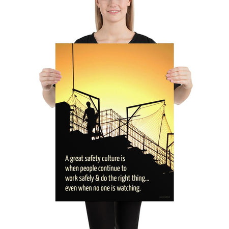 A construction safety poster showing the silhouette of a construction worker working on a building with a bright yellow sunset in the background and a safety slogan in the bottom left corner.