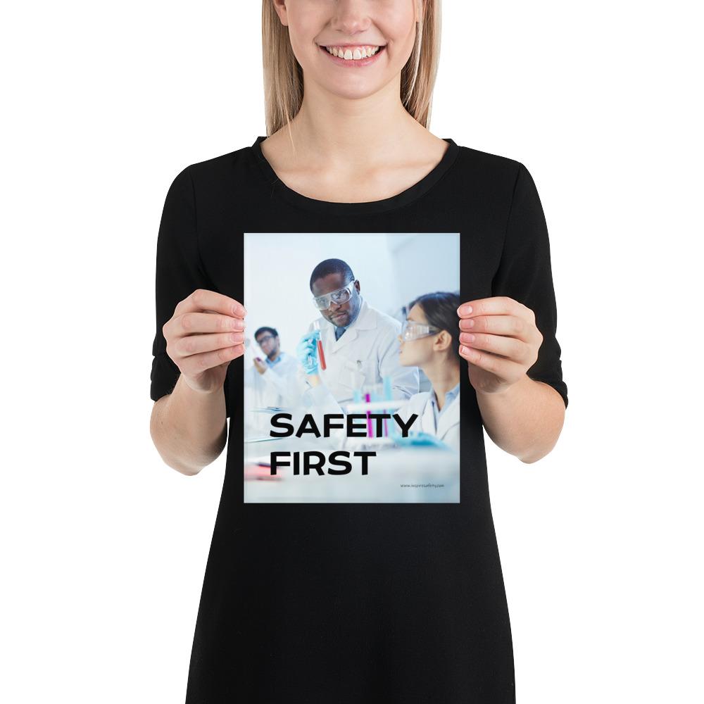 A safety poster showing two lab workers collaborating on a project in a lab while wearing full PPE with the slogan safety first.