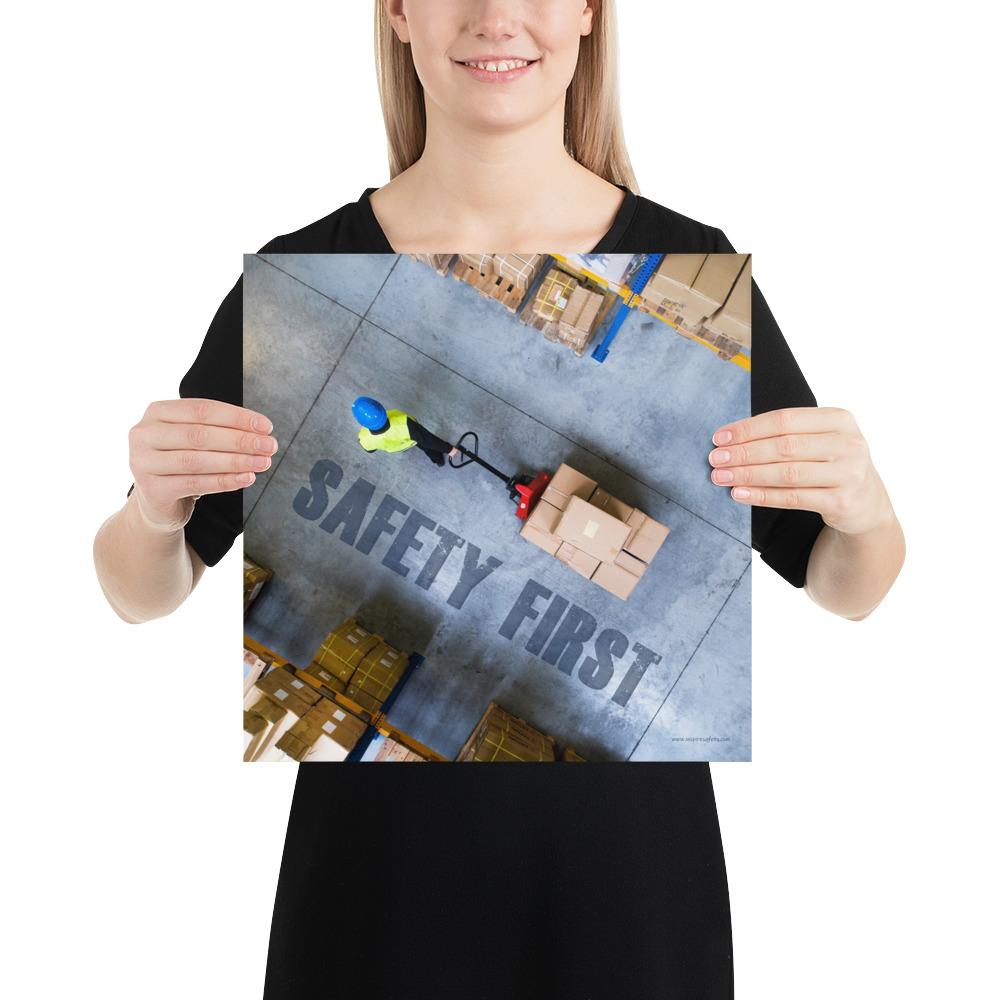 A safety poster showing a bird's-eye view of a worker in a warehouse pulling boxes on a pallet jack with the slogan safety first in bold letters.