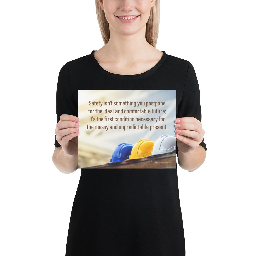 A workplace safety poster showing 3 multi colored hardhats sitting on a wall with the slogan safety isn't something you postpone for the ideal and comfortable future. It's the first condition necessary for the messy and unpredictable present.