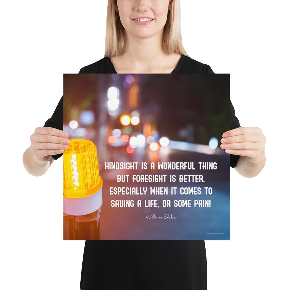 A workplace safety poster depicting a bright orange construction traffic light in the foreground of a blurry nighttime cityscape with a safety quote by William Blake.