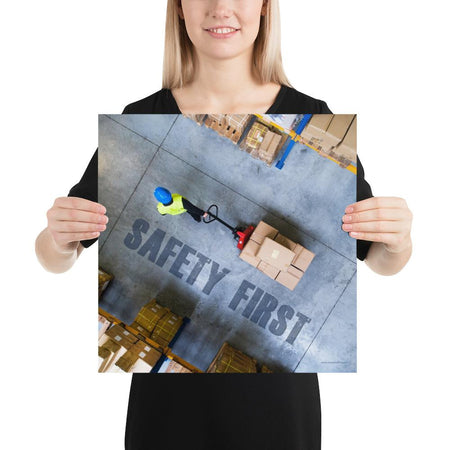 A safety poster showing a bird's-eye view of a worker in a warehouse pulling boxes on a pallet jack with the slogan safety first in bold letters.