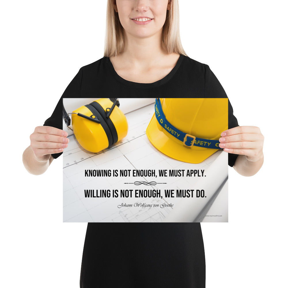 A safety poster showing a yellow hard hat and yellow ear muffs on blueprints with a safety quote by Johann Wolfgang von Goethe that says "Knowing is not enough, we must apply. Willing is not enough, we must do."