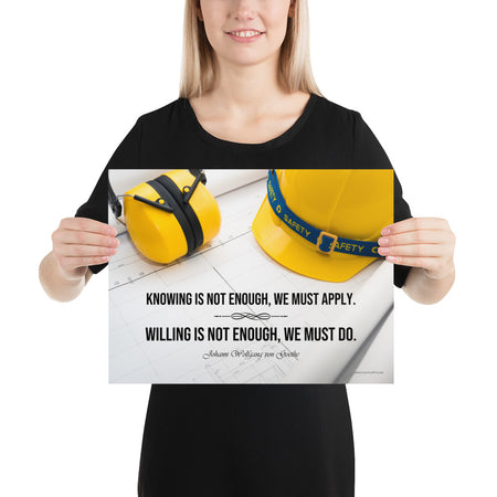 A safety poster showing a yellow hard hat and yellow ear muffs on blueprints with a safety quote by Johann Wolfgang von Goethe that says "Knowing is not enough, we must apply. Willing is not enough, we must do."