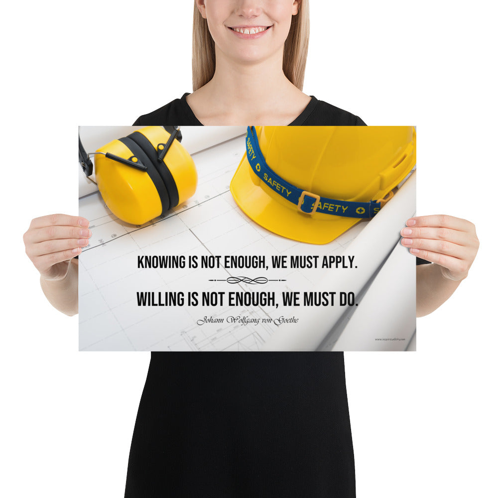 A safety poster showing a yellow hard hat and yellow ear muffs on blueprints with a safety quote by Johann Wolfgang von Goethe that says "Knowing is not enough, we must apply. Willing is not enough, we must do."