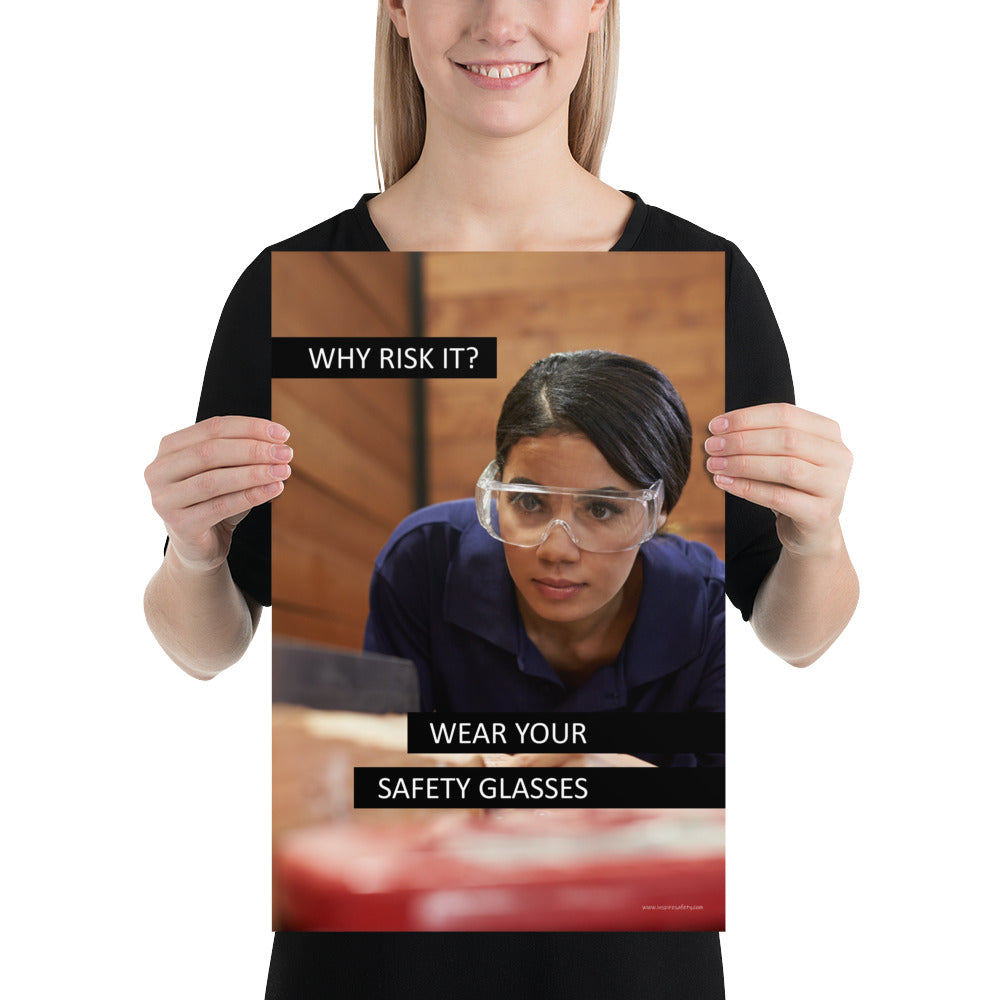 A safety poster showing a woman using a table saw to cut wood wearing safety glasses with the slogan "Why Risk It? Wear Your Safety Glasses."