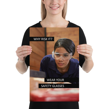 A safety poster showing a woman using a table saw to cut wood wearing safety glasses with the slogan "Why Risk It? Wear Your Safety Glasses."