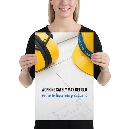 A construction safety poster showing yellow ear muffs and a hard hat resting on blueprints with the slogan "Working safely may get old, but so do those who practice it."