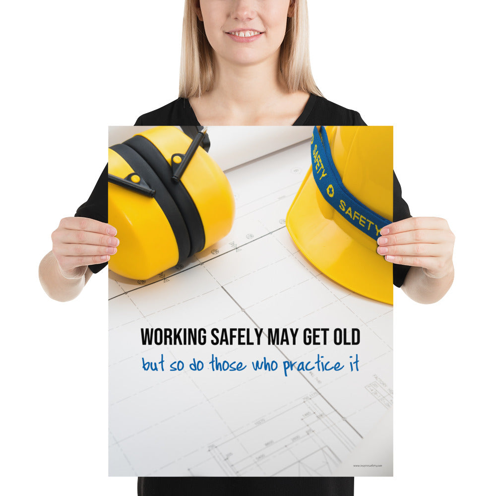 A construction safety poster showing yellow ear muffs and a hard hat resting on blueprints with the slogan "Working safely may get old, but so do those who practice it."