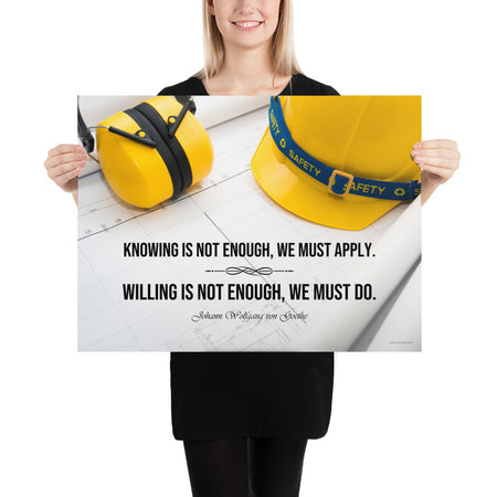 A safety poster showing a yellow hard hat and yellow ear muffs on blueprints with a safety quote by Johann Wolfgang von Goethe that says "Knowing is not enough, we must apply. Willing is not enough, we must do."