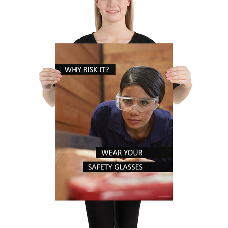 A safety poster showing a woman using a table saw to cut wood wearing safety glasses with the slogan "Why Risk It? Wear Your Safety Glasses."