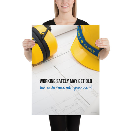 A construction safety poster showing yellow ear muffs and a hard hat resting on blueprints with the slogan "Working safely may get old, but so do those who practice it."