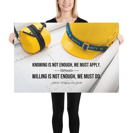 A safety poster showing a yellow hard hat and yellow ear muffs on blueprints with a safety quote by Johann Wolfgang von Goethe that says "Knowing is not enough, we must apply. Willing is not enough, we must do."