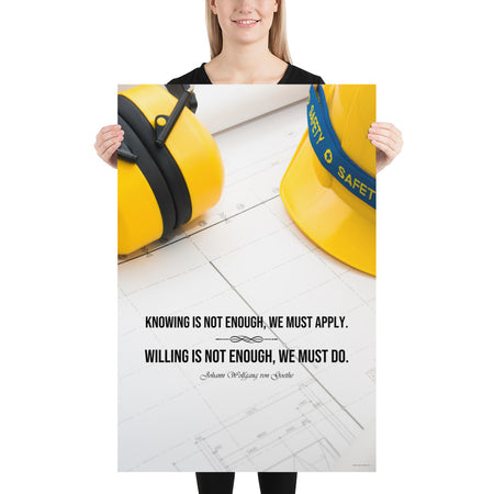 A safety poster showing a yellow hard hat and yellow ear muffs on blueprints with a safety quote by Johann Wolfgang von Goethe that says "Knowing is not enough, we must apply. Willing is not enough, we must do."