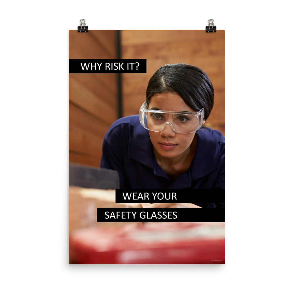 A safety poster showing a woman using a table saw to cut wood wearing safety glasses with the slogan "Why Risk It? Wear Your Safety Glasses."