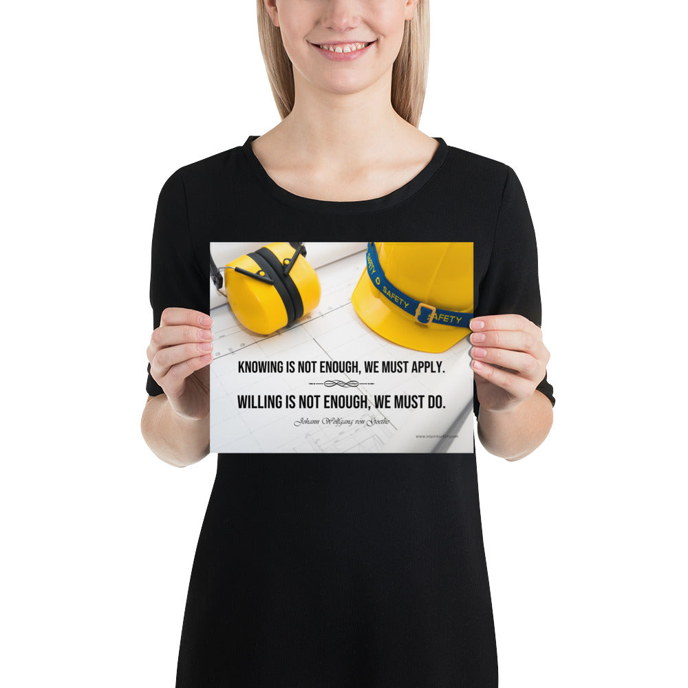 A safety poster showing a yellow hard hat and yellow ear muffs on blueprints with a safety quote by Johann Wolfgang von Goethe that says "Knowing is not enough, we must apply. Willing is not enough, we must do."