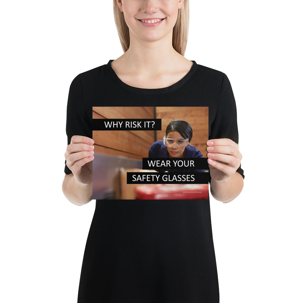 A safety poster showing a woman using a table saw to cut wood wearing safety glasses with the slogan "Why Risk It? Wear Your Safety Glasses."